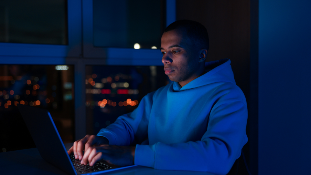 شخص يعمل على اللابتوب ليلاً في بيئة رقمية للعمل عن بعد